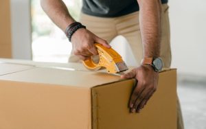 A man taping cardboard box with scotch